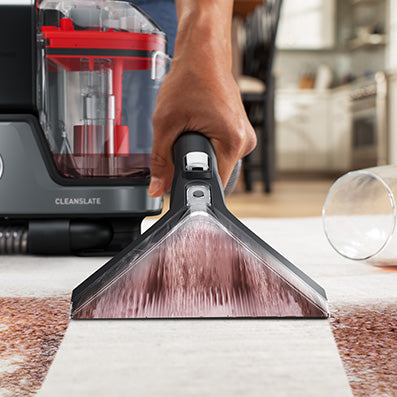 Close up of cleanslate cordless spot cleaner in action efficiently removing a dark colored stain from a white carpet, showcasing its outstanding cleaning power and performance