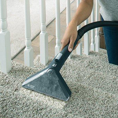 Using a Hoover upholstery brush to clean carpeted stairs showcasing spot cleaning capabilities