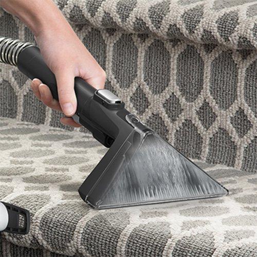 Close up of a Hoover Cleanslate upholstery tool being used on patterned stairs, showcasing its powerful suction for effective carpet and upholstery cleaning