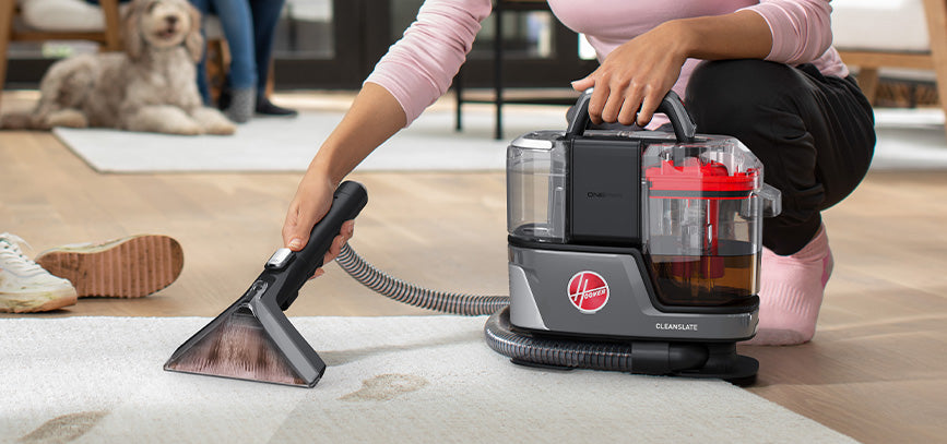 Cleanslate portable spot cleaner is being used to remove muddy footprint stains from a light colored carpet