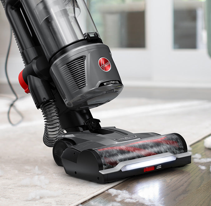 Hoover vacuum cleaner with tangleguard technology and powerful suction in action, efficiently cleaning cotton from a hard floor and area rug.  