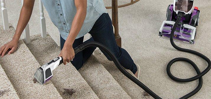 Hoover smartwash pet complete is showcasing its versatile cleaning capabilities with a woman spot cleaning her stairs using the 8ft hose and spot cleaning tool