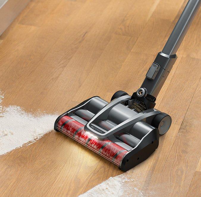 A hoover vacuum cleaner demonstrating its powerful suction with dual cyclonic filtration on a hardwood floor, effectively picking up spilled flour.