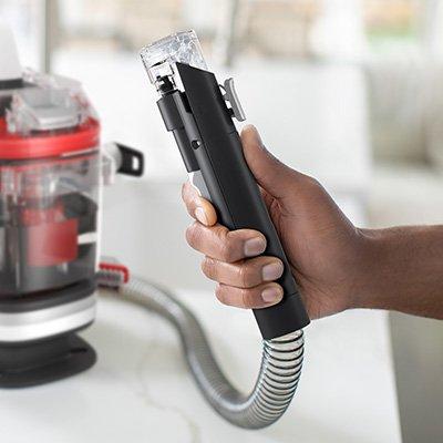 Close up of someone holding the Cleanslate portable spot cleaner hose rinse tool attachment used for efficient cleaning 