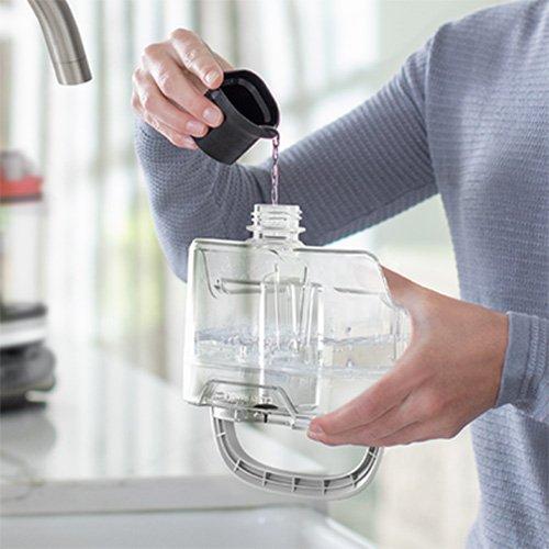 Person effortlessly pouring cleaning solution into the tank of a Hoover Cleanslate pet cleaner showing its easy maintenance and user friendly capabilities