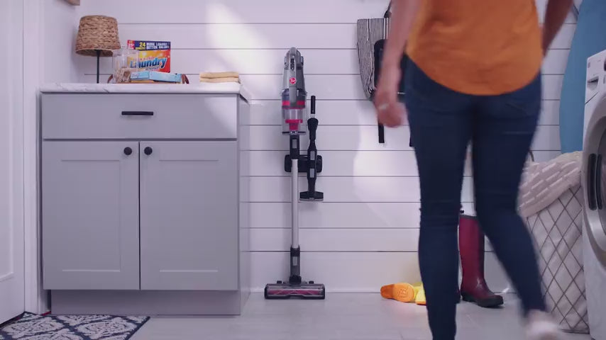 Load video: Woman using her cordless Hoover emerge vacuum cleaner to vacuum multiple surfaces in her home, highlighting its convenience, flexibility and versatile cleaning. 