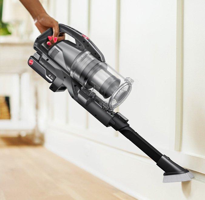 Person using the Hoover 2 in 1 tool attachment to clean tight hard-to-reach areas and remove dust from delicate surfaces like baseboards.