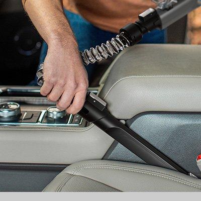 Close up of hand using the powered extension hose to clean car interior, demonstrating its versatility and added reach.