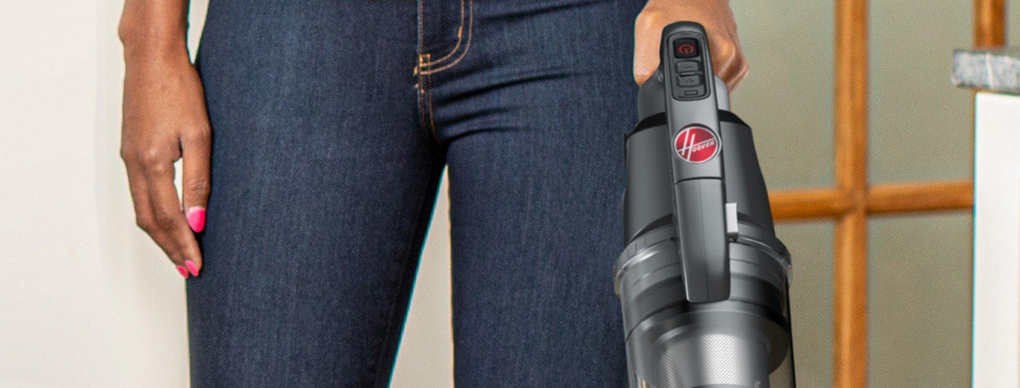 Close up view of the top of Hoover vacuum cleaner being held by a person, showcasing the ergonomic design and easy-to-use controls. 