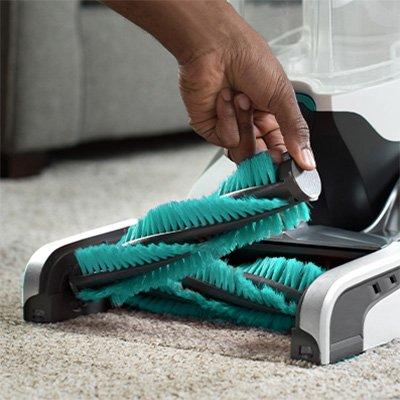 Hand removing the brushroll from a Hoover carpet cleaner highlighting easy clean up.