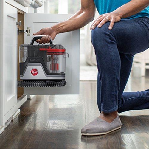 Person placing the compact and portable Hoover Cleanslate pet cleaner back in the kitchen cabinet showcasing its easy storage