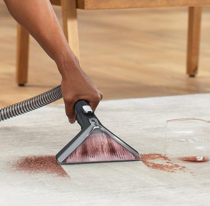 Close up of cleanslate cordless spot cleaner in action efficiently removing a dark colored stain from a white carpet, showcasing its outstanding cleaning power and performance