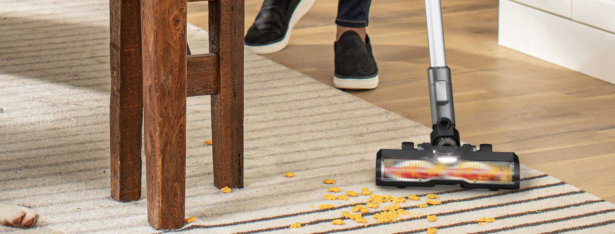 Close up of Hoover cordless vacuum cleaner effortlessly cleaning goldfish off a light colored carpet.