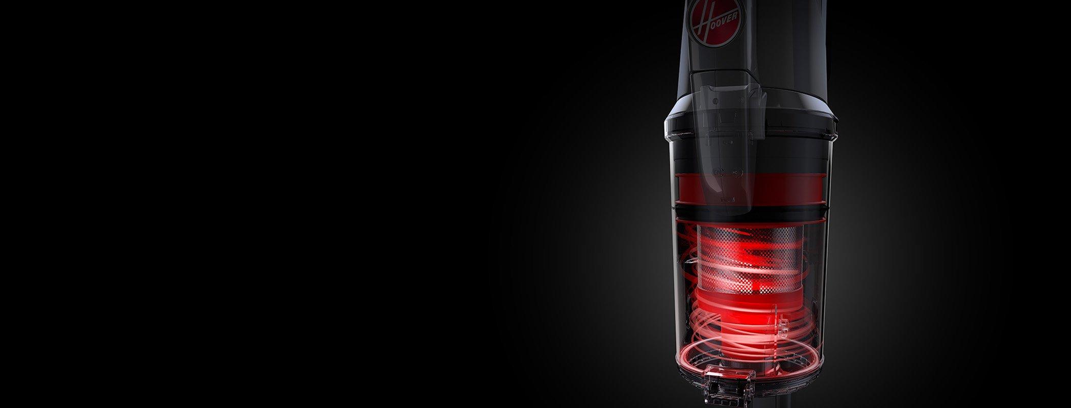 Close up of the Hoover vacuum cleaner's transparent canister showcasing the red cyclonic filtration system in action against a black background.  