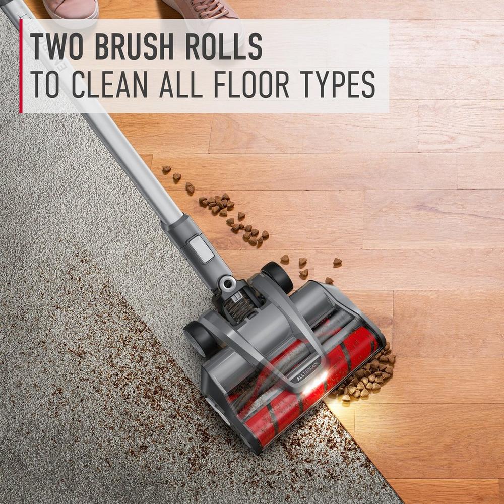 Hoover vacuum cleaner demonstrating its ability to clean both carpet and hard floor types with two brush rolls.  The vacuum is shown picking up pet food from both surfaces, highlighting its versatility 