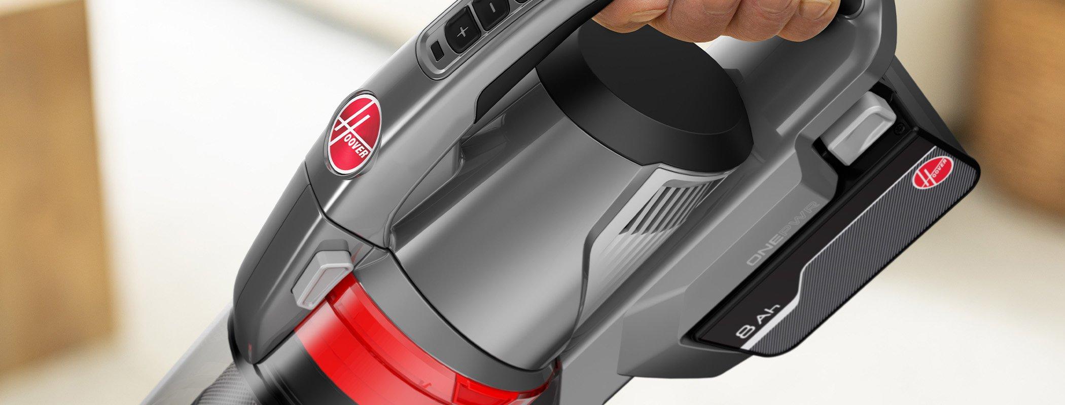 Close-up image of a Hoover cordless vacuum cleaner with a focus on the handle and 4Ah ONEPWR lithium-ion battery being inserted, highlighting ease of use and power.