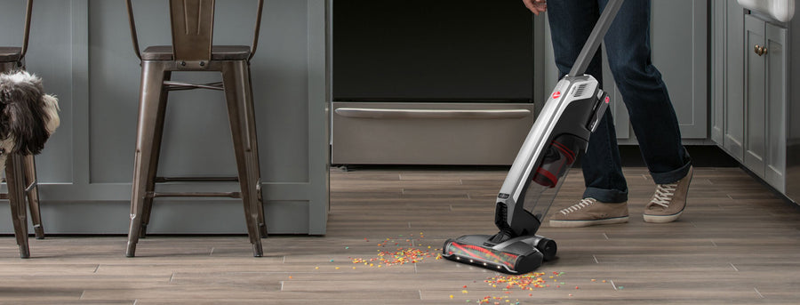 Man is using his evolve pet elite to clean cereal off his hardwood floors