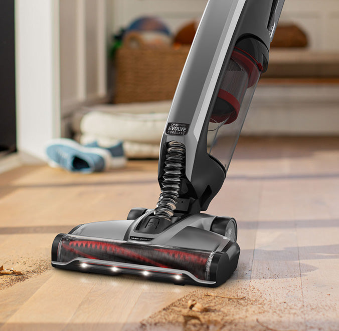 Evolve pet elite shown in action highlighting its powerful suction by cleaning up dirt and debris from a hard wood floor