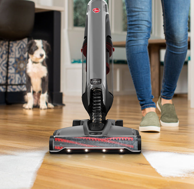 Evolve pet elite shown vacuuming sugar up from hard wood floors as dog watches