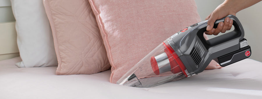 Hoover handheld vacuum cleaner being used to clean upholstery.