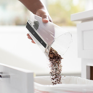 Hoover handheld vacuum cleaner dustbin being emptied in a trashcan showcasing its easy maintenance.