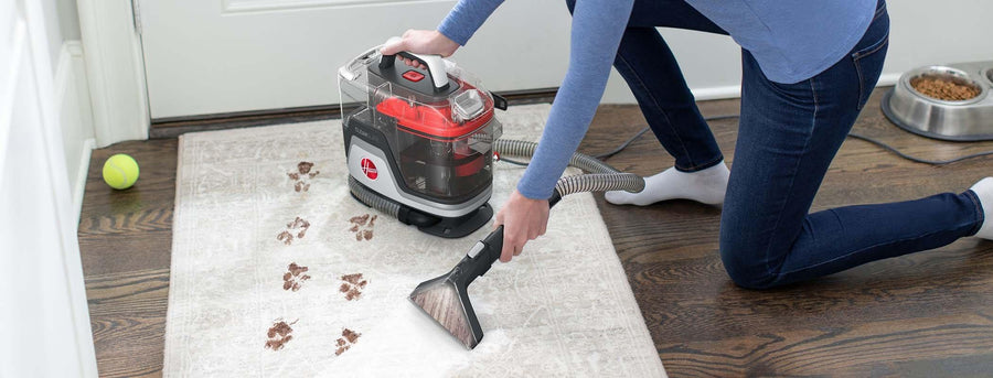 Woman shown using her cleanslate pet to spot clean paw prints off a light gray area rug