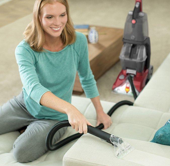 Woman smiling as she easily uses the Hoover power scrub carpet cleaner to deep clean her couch