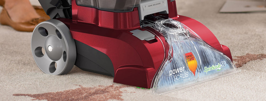 Close up of Hoover power scrub deluxe head in action, removing a deep red liquid stain from a light colored carpet 