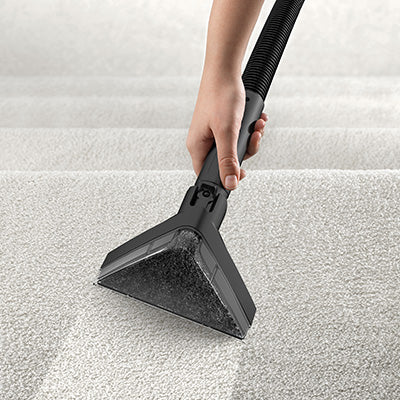 Person using a Hoover power scrub carpet cleaner on stairs with the upholstery attachment to deep clean the stairs