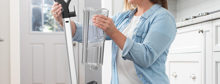 Woman inserting her larger clean water tank into her powerdash pet advanced carpet cleaner highlighting that you can now have fewer fill ups and longer clean time