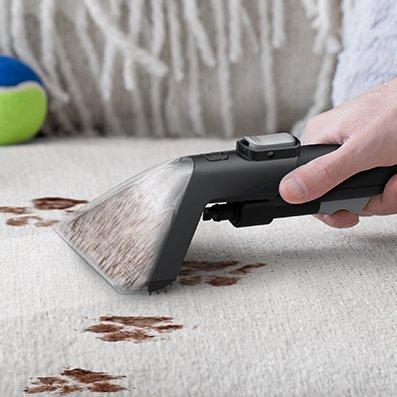 Close up of someone effectively spot cleaning dirt stains out of couch upholstery