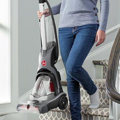 Woman easily carrying her powerdash pet advanced down the stairs showcasing its compact convenience.  She is able to grab and go since her powerdash pet advanced has a portable and lightweight design.