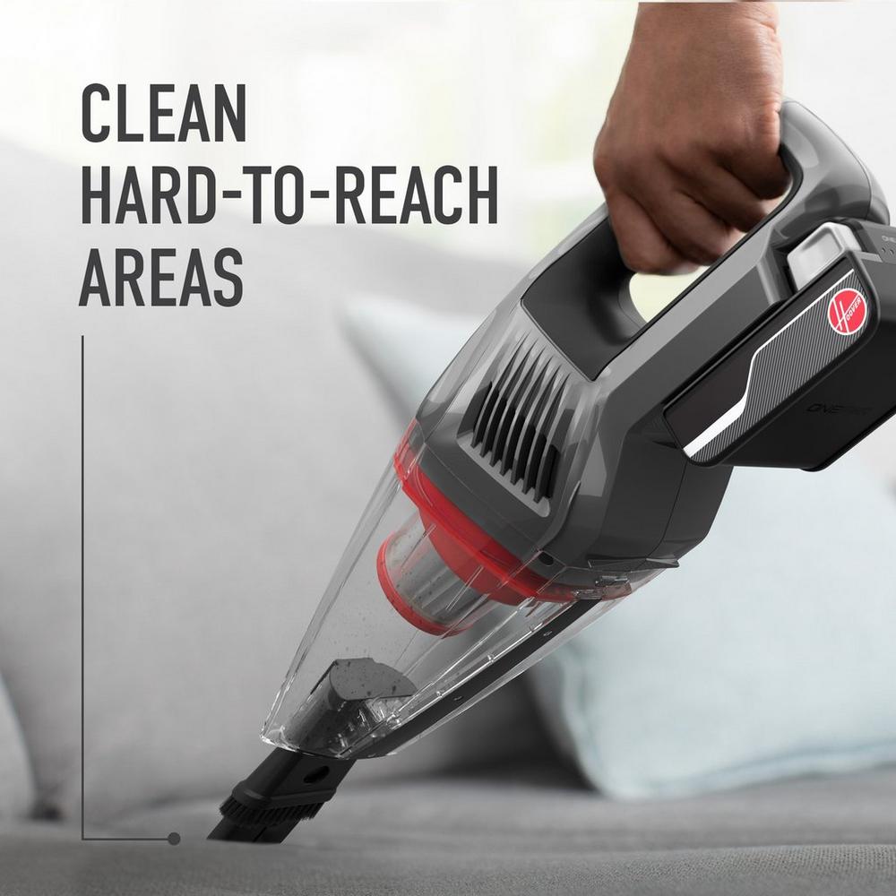 Hoover handheld vacuum is being used with its 2-in-1 crevice tool and dusting brush to clean a couch highlighting its ability to clean hard-to-reach areas.