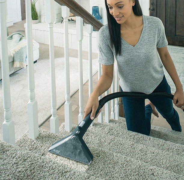 A woman used the 8 ft. hose and stair tool to convert her carpet cleaner to a spot cleaner.  She is spot cleaning her stairs.