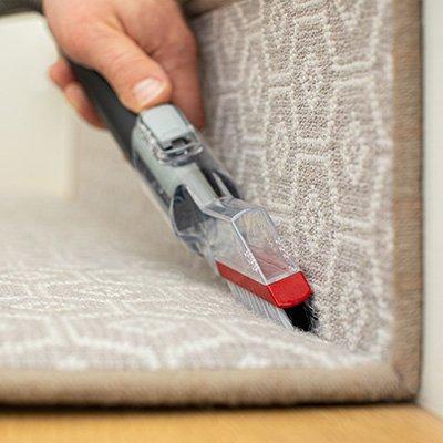 Close up of Cleanslate pet carpet and upholstery tight spot tool being used in stair crevices to effectively clean tight spaces 