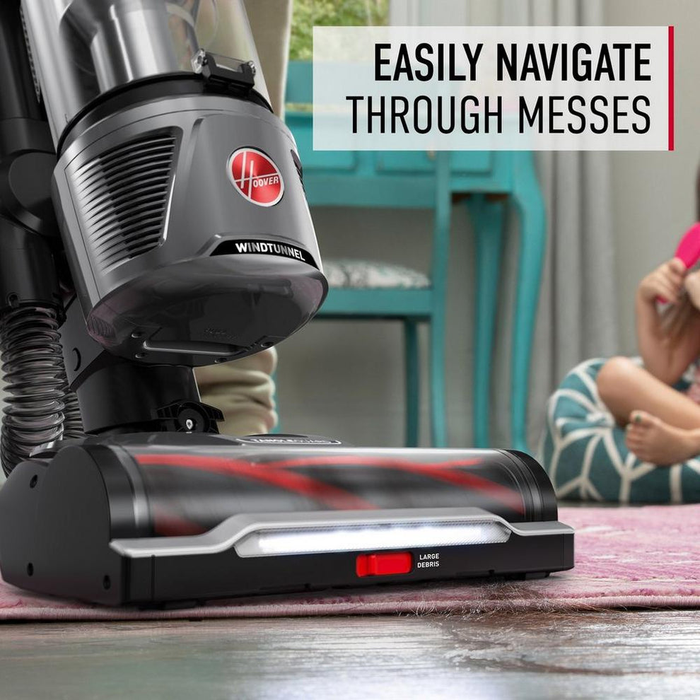 Close up of hoover windtunnel vacuum cleaner navigating through messes by vacuuming hair from an area rug.