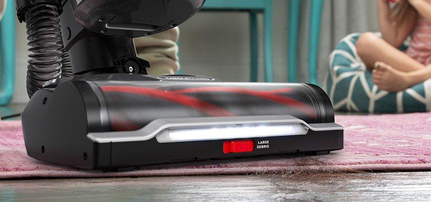 Close up of hoover windtunnel vacuum cleaner navigating through messes by vacuuming hair from an area rug.