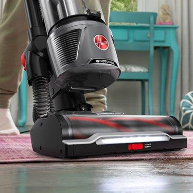 Close up of hoover windtunnel vacuum cleaner navigating through messes by vacuuming hair from an area rug.