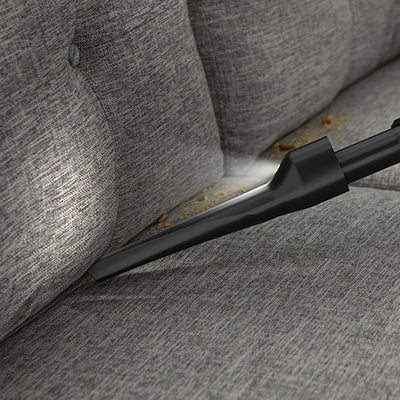 Close up of the LED crevice tool in action, vacuuming the tiny crumbs on a couch, that are clearly visible with the tool