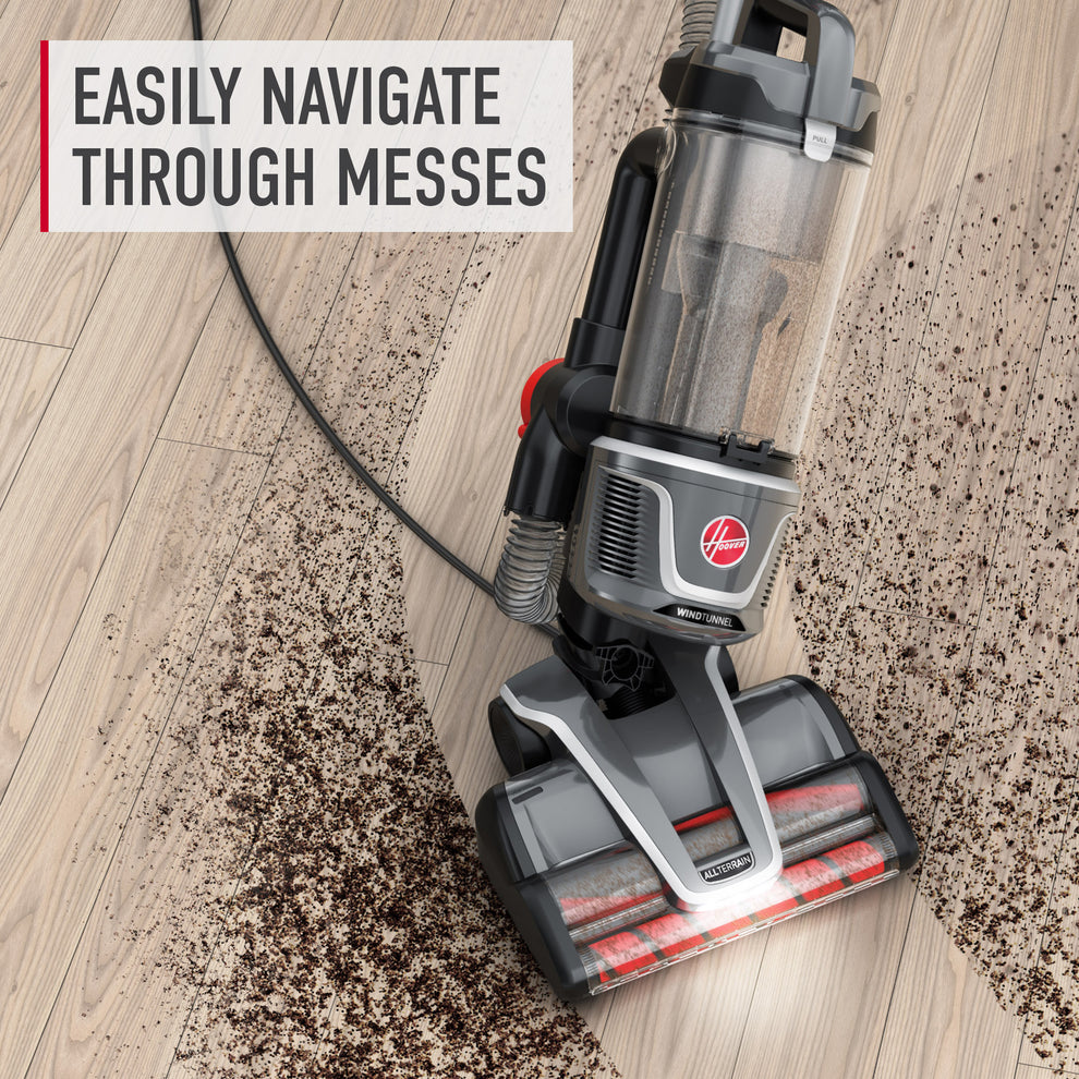 Hoover vacuum cleaner navigating through a large dirt mess on a wooden floor, highlighting its easy maneuverability.