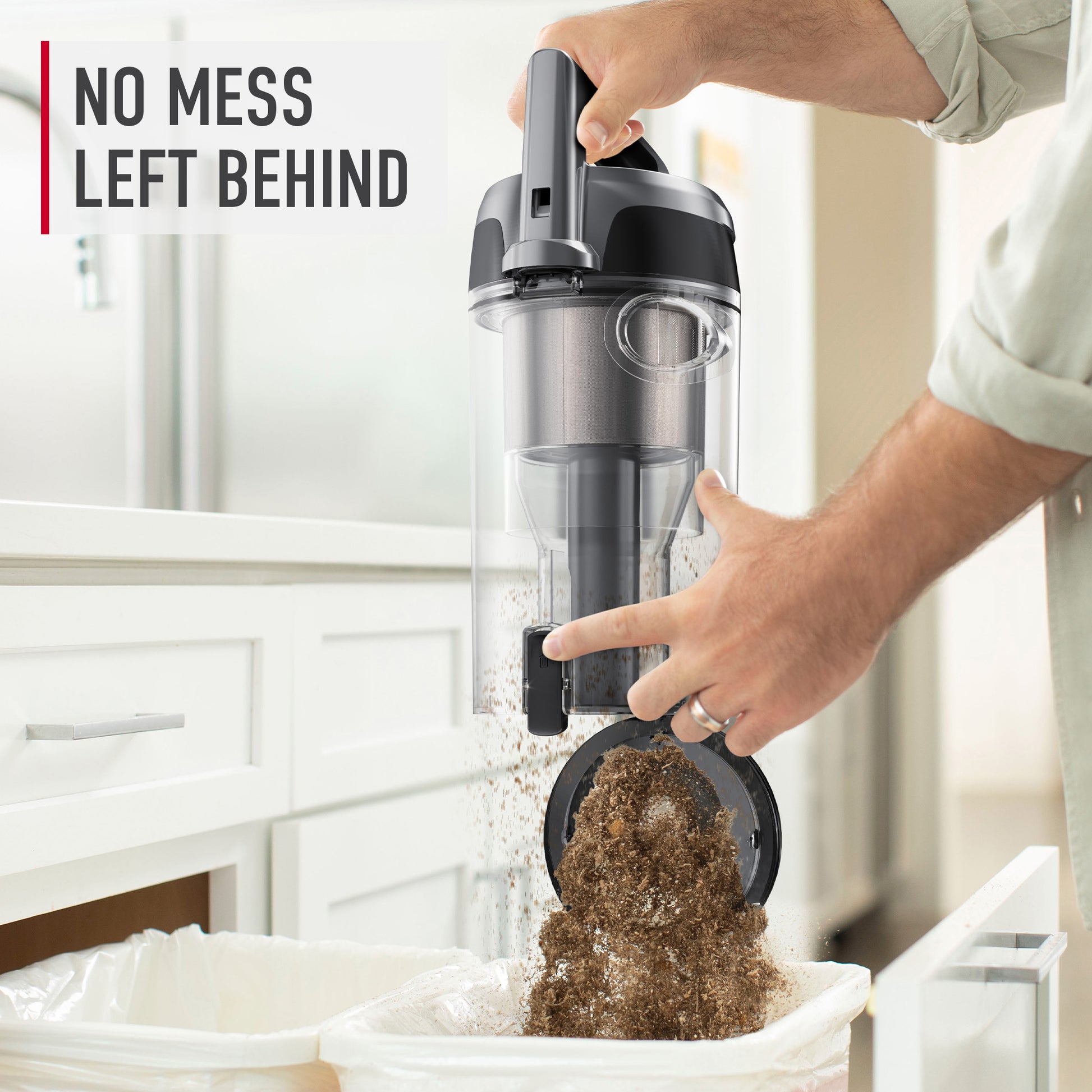 Close up of a person emptying the dirt cup of a Hoover windtunnel vacuum cleaner into a trash can, emphasizing the vacuum's easy maintenance